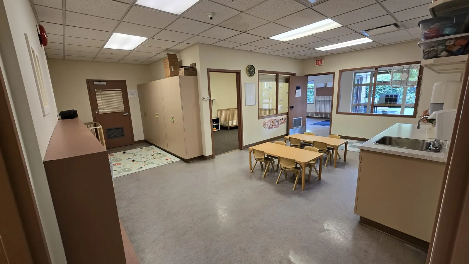 the infant nap room with cribs, seen through the doorway from the toddler room at our Fleetwood centre