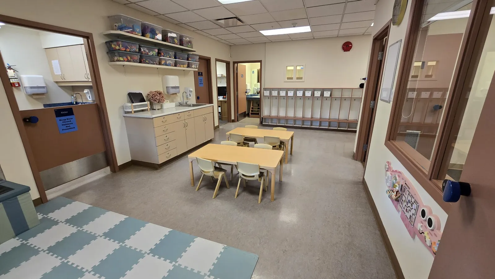 toy bins on the shelves, soft foam mats, low tables and cubbies in the toddler room